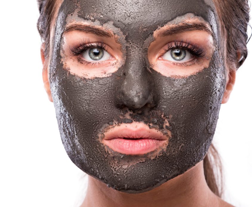 Beautiful woman with a clay or a mud mask on her face